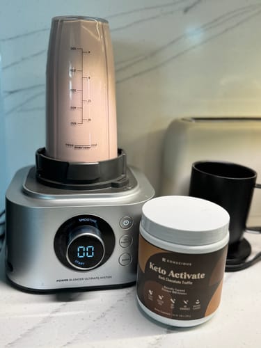 Customer's tub of Keto Activate Dark Chocolate Truffle next to a prepared chocolate smoothie in a blender.