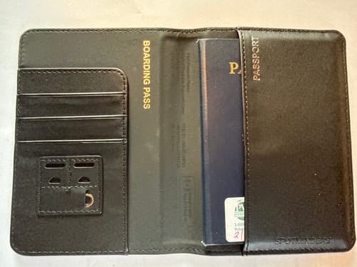 Customer's open black Trackable Passport Cover showing the interior with a passport, card slots, and boarding pass holder.