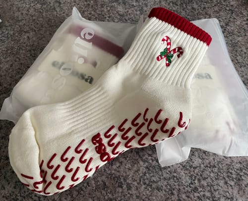 Reviewer's off-white Candy Cane socks with a red cuff, candy cane embroidery, and red grippers on the sole.