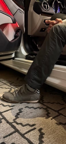 Customer in a car wearing the Titanium Grey Racing Sneaker, showing the checkered detail on the heel.
