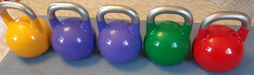Reviewer's five vividly painted Stainless Steel Competition Kettlebells lined up.
