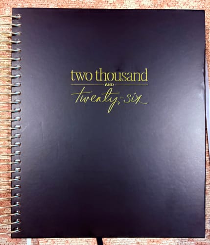 Customer's black 2026 Signature Planner, showing the gold foil text on the cover and gold spiral binding.
