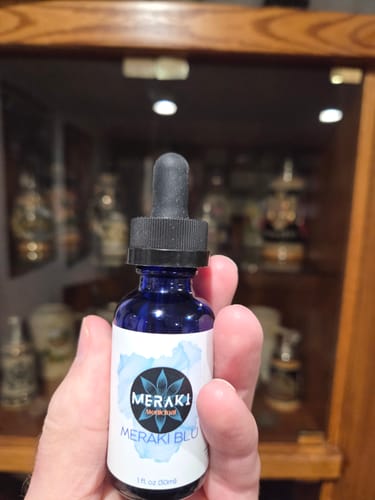 Reviewer holding the blue Meraki Blu dropper bottle in their hand.