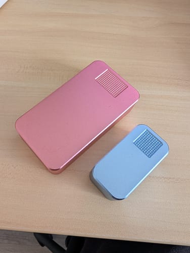 Customer's pink and light blue pill cases from the 2-pack bundle on a wooden desk.