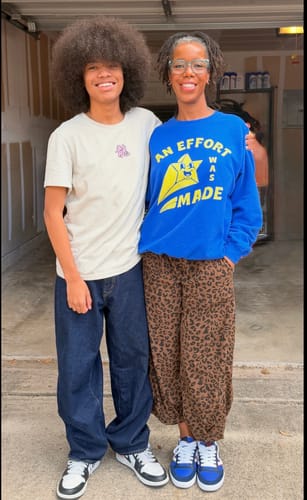 Reviewer wearing the blue An Effort Was Made Sweatshirt for a baggy fit while standing next to another person.