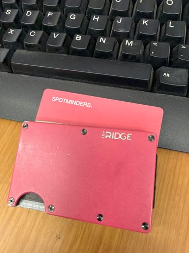 Customer's red SPOTMINDERS. Tracking Card shown inside a red minimalist wallet on a desk.