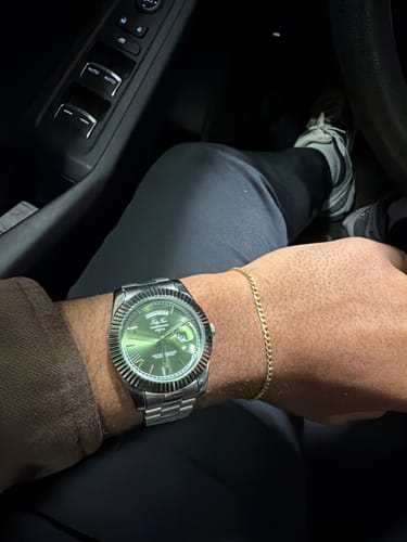 A reviewer's wrist wearing the Lucky Fours® Santos watch, showing its green dial and silver band.