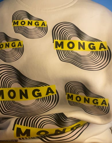 Close-up of a customer's white oversized sweatshirt featuring a repeating black and yellow graphic with the word 'MONGA'.
