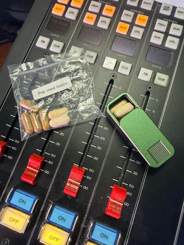 Reviewer's green Nano Pill Case, open with supplements inside, shown next to a plastic bag of pills.