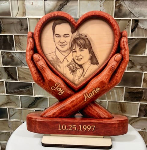 Customer's Custom Couple Photo Anniversary wooden plaque in a heart-shaped design held by carved hands with engraved names.
