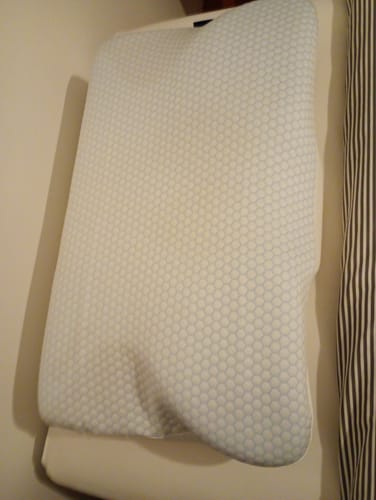 Customer's Oreiller Papillon Cervical Cellsius avec une surface texturée bleue et blanche posé sur un lit.