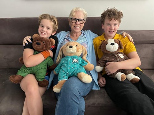 Customer's children and adult holding three Hond Kleding Origineel Lotgenootje plush toys in pajamas on a sofa.