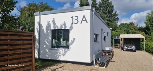 Kundenfoto der montierten, dunklen Hausnummer 13 A am weißen Hausfassade.