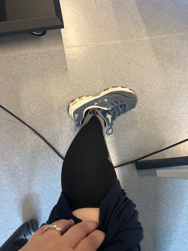 Customer's black Luvinya compression sock worn on the leg with a blue sneaker in a bright room.