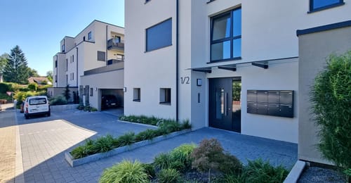 Kundenfoto der montierten, dunklen WesterWerk-Hausnummer 1/2 an einer modernen Hausfassade.