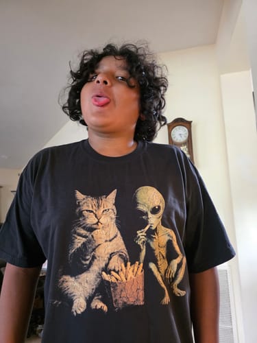 Customer's Close Encounters shirt featuring a cat and alien eating fries, worn by a person making a silly face.