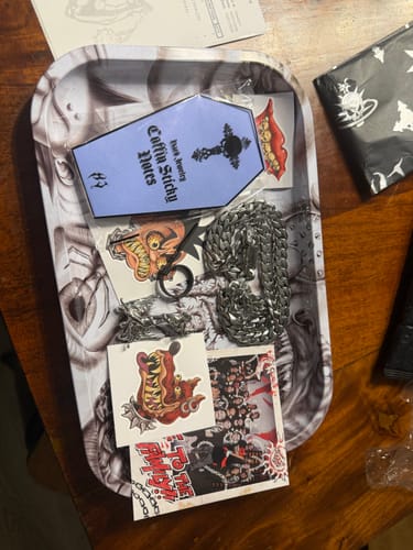 Customer's FREE XL JEWELRY TRAY containing silver chains, a pendant, and assorted stickers on a wooden table.