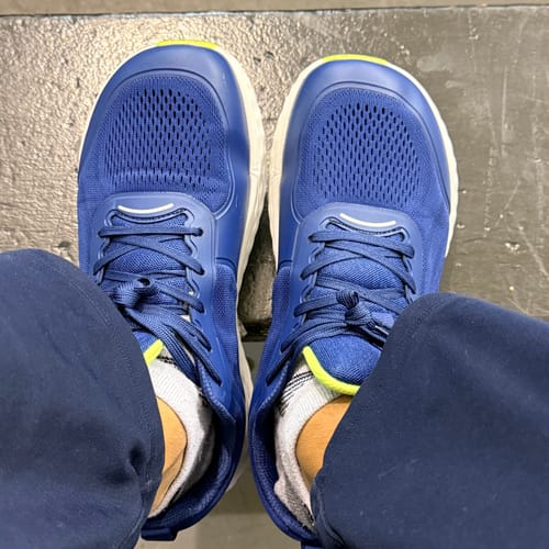 Customer's feet wearing blue Mystery Gift walking shoes with white soles and laces, showing mesh fabric.