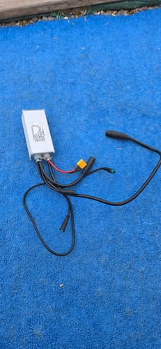 Customer's CMACEWHEEL V20 Controller, a silver rectangular metal box with several thick black cables, on blue ground.