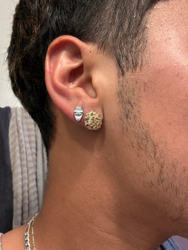 Customer's silver Comedy Mask stud earring worn on their earlobe.