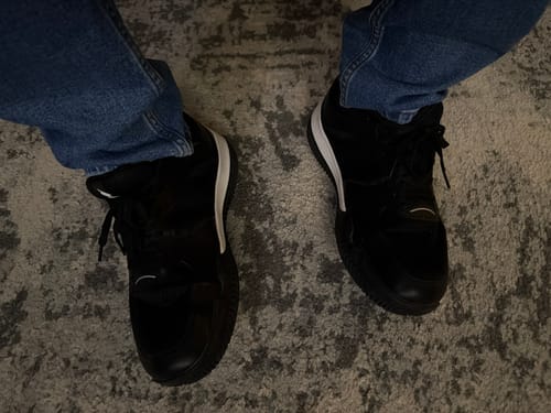 Reviewer's black CUURT Muuv court shoes worn with blue jeans, viewed from above on a textured rug.