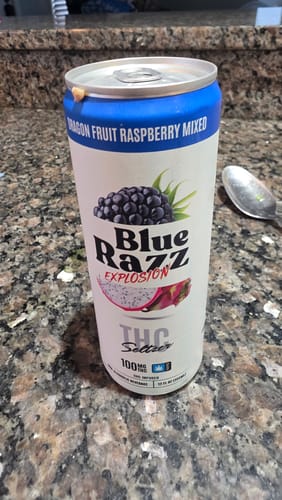 Customer's Blue Razz Explosion 100MG THC infused soda can resting on a kitchen counter next to a spoon.