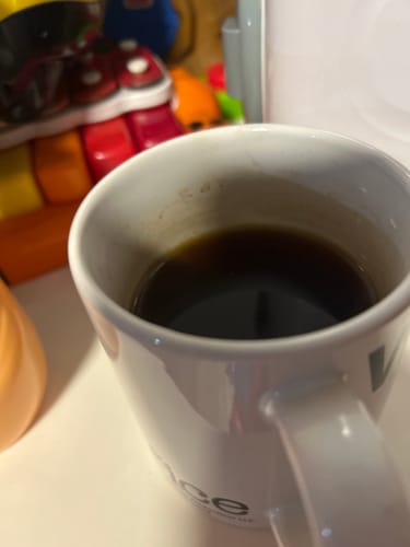 Reviewer's Organic Nepal Black Tea in a white mug, next to a colorful toy.