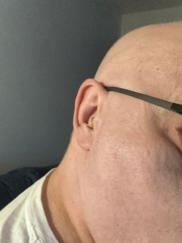 Reviewer's Future Hearing Comfort Hearing Aid in ear, showing how it fits comfortably behind glasses.