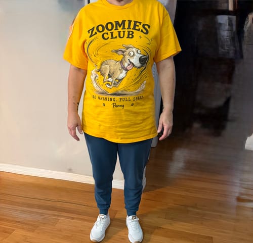 Customer's yellow Zoomies Club personalized shirt with a custom dog portrait and the dog's name worn by a person.