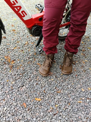 Reviewer's brown Vaistoa Uoma 2 barefoot hiking boots worn outdoors on a gravel path near a bicycle.