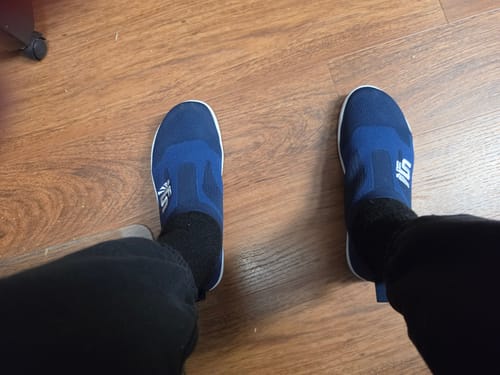 Customer's pair of blue The Otishi 2.0 Low slip-on shoes worn on feet on a wooden floor.