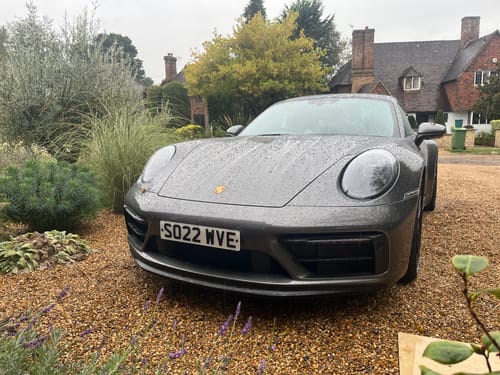 Customer's grey Porsche 911 parked on gravel with the miniature plinth installed on the front bumper.