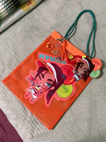 Customer's Alien Stage orange mesh bag adorned with a character print, green straps, and several decorative keychains.