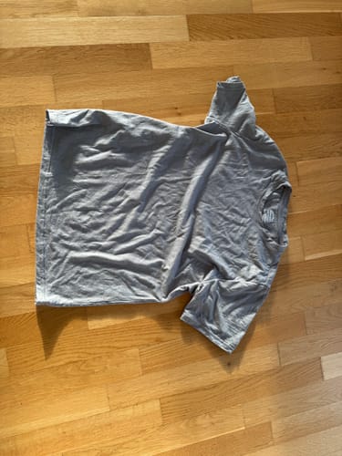 Customer's graues Merino Shirt Herren, flach auf einem Holzboden liegend.
