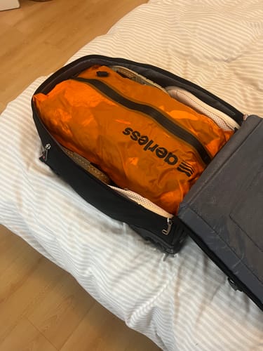 Customer's open luggage packed with a bright orange Aerless compression bag inside.