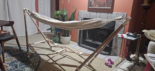Customer's The Go Hammock set up in a living room near a fireplace and potted plants.
