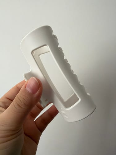 Customer holding a white, matte-finish rectangular hair clip in their hand.