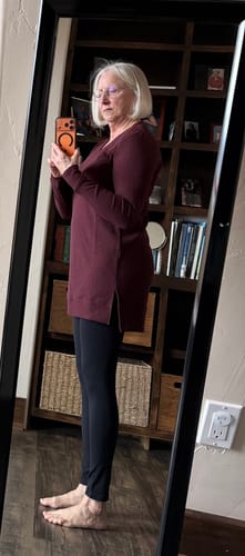 Reviewer's side profile wearing the black Ellis Seamless Petite Tights layered under a long maroon top.