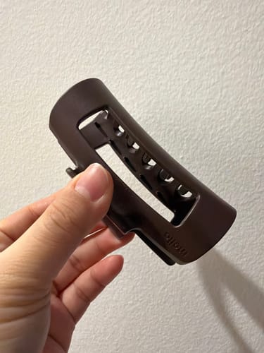 Customer holding a dark brown Mello clip against a plain white wall.