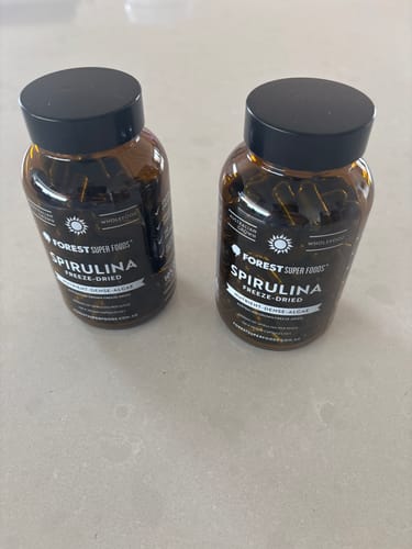 Reviewer's two amber bottles of Australian Freeze Dried Spirulina sitting on a countertop.