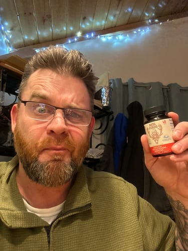 Customer holding a bottle of Primal Reindeer Testosterone Support supplement indoors.