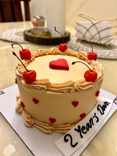 Customer's Cherry Valentine Cake on a table, decorated with cherries, red hearts, and a "2 Year's Down" banner in front.