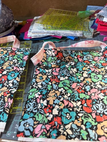 Partial view of a customer's Creative Grids Cutting Mat covered with colorful fabric and sewing projects.