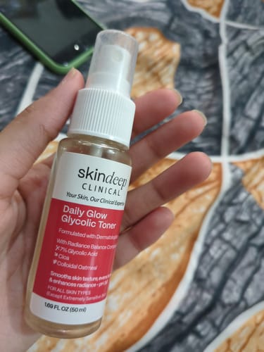Customer holds a spray bottle of the Daily Glow Glycolic Toner in their hand, showing the label.