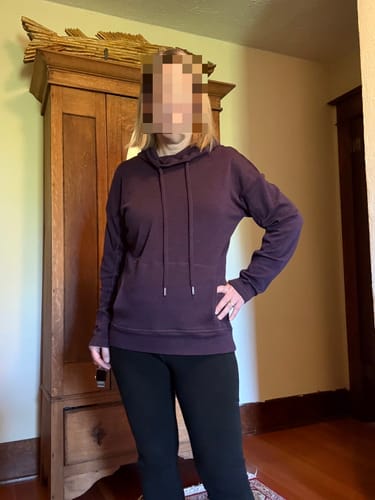 Reviewer wearing the size medium Callie Hoodie in Deep Plum paired with black leggings indoors.
