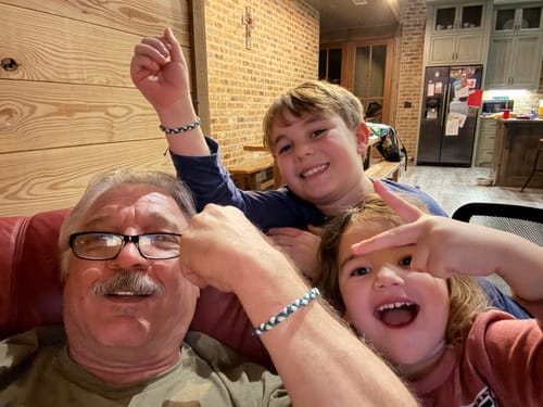Reviewer and two children happily displaying their matching woven DAVID Bracelets on their wrists.