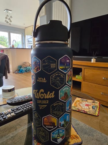 Customer's World Explorer Bottle on a living room table, decorated with colorful destination stickers.