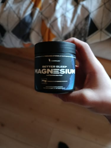 Customer holding a black tub of Sleep Magnesium in their hand.