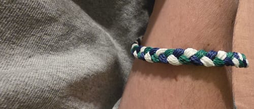 Close-up of the braided DAVID Bracelet in blue, green, and white on a reviewer's arm.