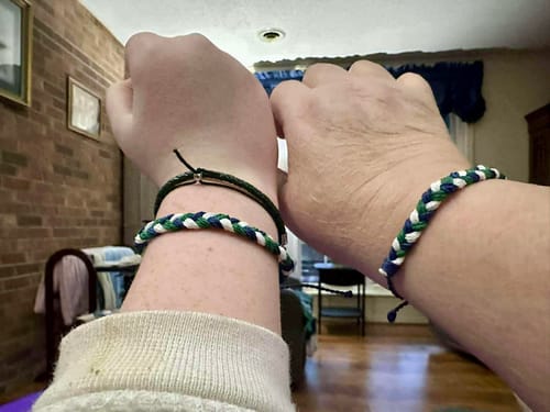 Reviewer and another person showing their matching woven DAVID Bracelets on their wrists side-by-side.